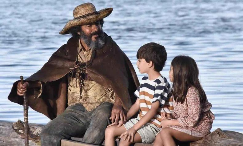 José Leôncio, agora Velho do Rio, conta histórias da menina-onça para os netos(foto: Globo/reprodução) Ator Marcos Palmeira com crianças em cena de Pantanal
