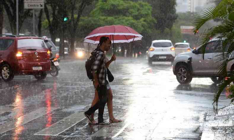 Imagem de pessoas andando na rua debaixo de chuva