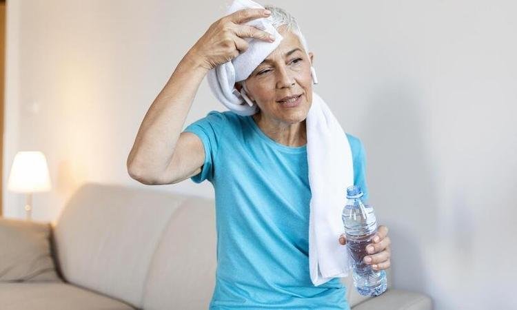  mulher s�nior segurando garrafa pl�stica de suor com uma toalha exausta ap�s o treinamento di�rio