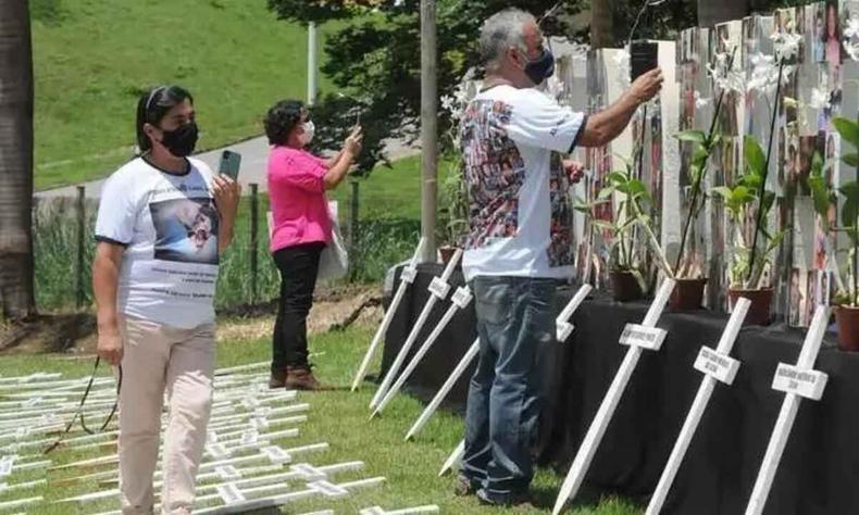 Vítimas do rompimento da barragem da Vale são regularmente lembradas por familiares e amigos em homenagens(foto: Túlio Santos/EM/D.A Press - 2/11/21) Pessoas colocam flores em crucifixos que relembram mortos após rompimento de barragem de rejeitos de mineração em Brumadinho