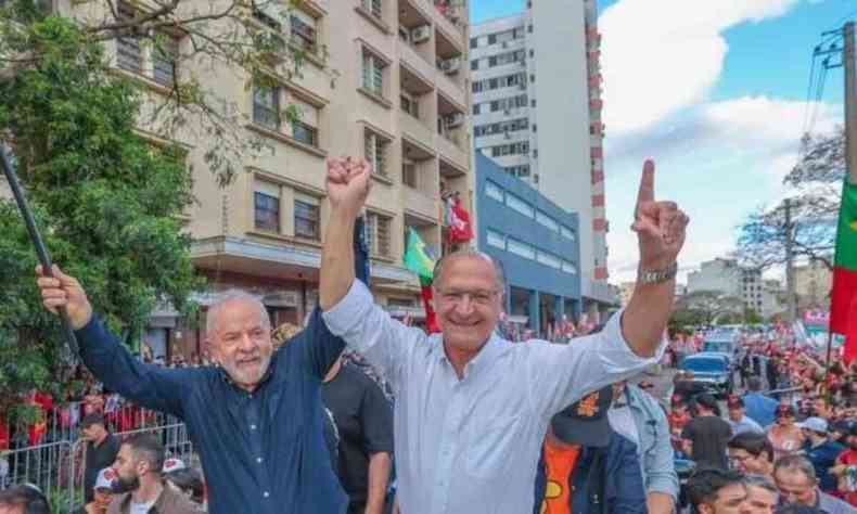 Lula e Alckmin em Comcio. Lula um homem branco, veste camisa azul com os braos para cima. Alckmin, homem branco, tambm com os braos para cima veste para cima, veste camisa social branca
