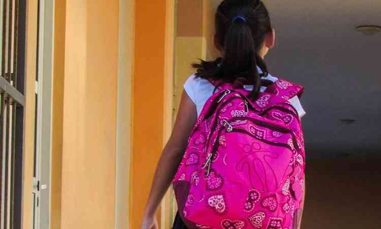 menina com mochila nas costas andando no corredor da escola