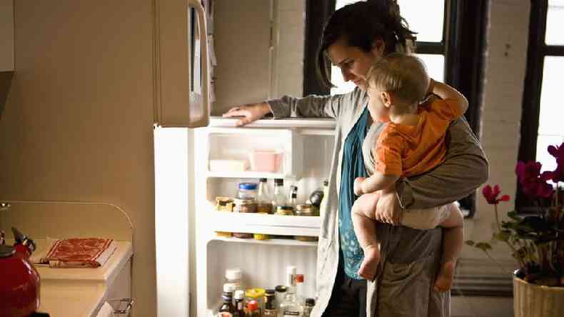 Mulher na frente de uma geladeira com seu filho