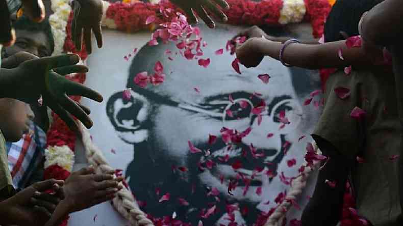 Mos jogando ptalas de flores em retrato de Mahatma Gandhi