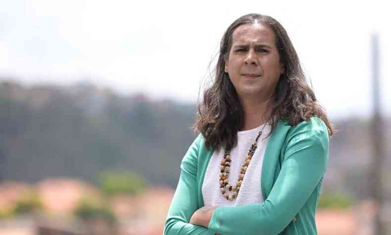 Duda Salabert, mulher trans usando blusa branca com um blaser verde claro