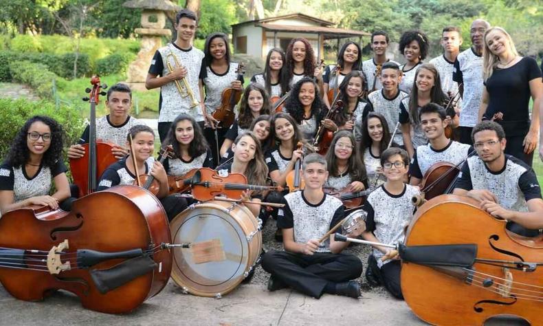 Num parque, jovens e crianas participantes da Orquestra Jovem Gerais posam para foto com seus instrumentos musicais