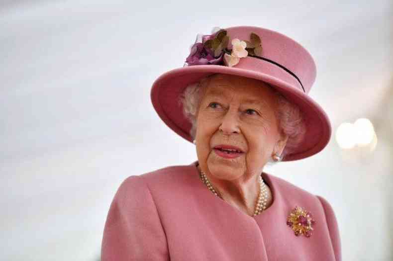 De roupa e chapu rosa, a rainha Elizabeth II olha para o lado 