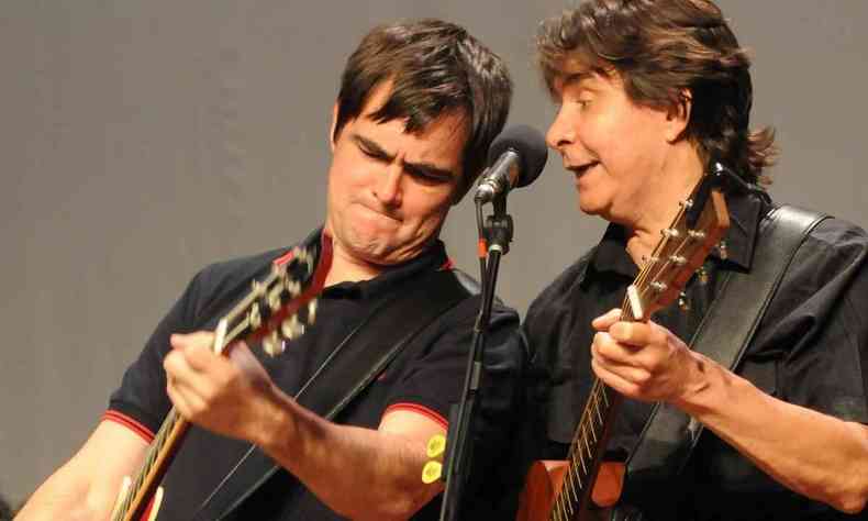 Samuel Rosa e L Borges tocam guitarra e cantam ao microfone, lado a lado