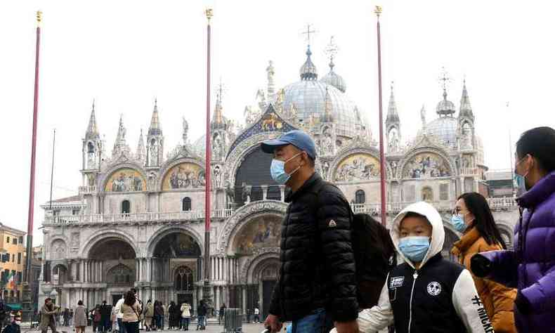 Turistas na Piazza San Marco, em Veneza, se protegem com mscaras do coronavirus (foto: ANDREA PATTARO/AFP)