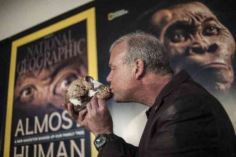 Professor Lee Berger beija caveira encontrada em caverna; atrs, cartaz com a imagem do possvel Homo naledi(foto: Stefan Heunis/AFP)