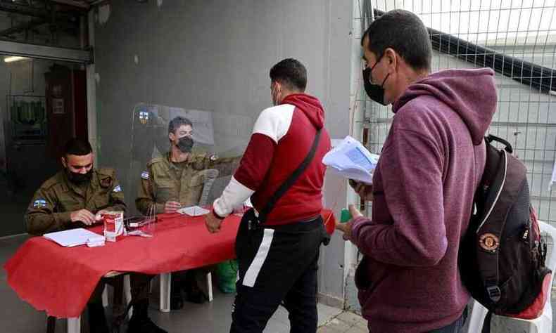 Palestinos que trabalham em Israel chegam a um posto para receber uma dose da vacina contra o coronavrus Moderna(foto: MENAHEM KAHANA / AFP)