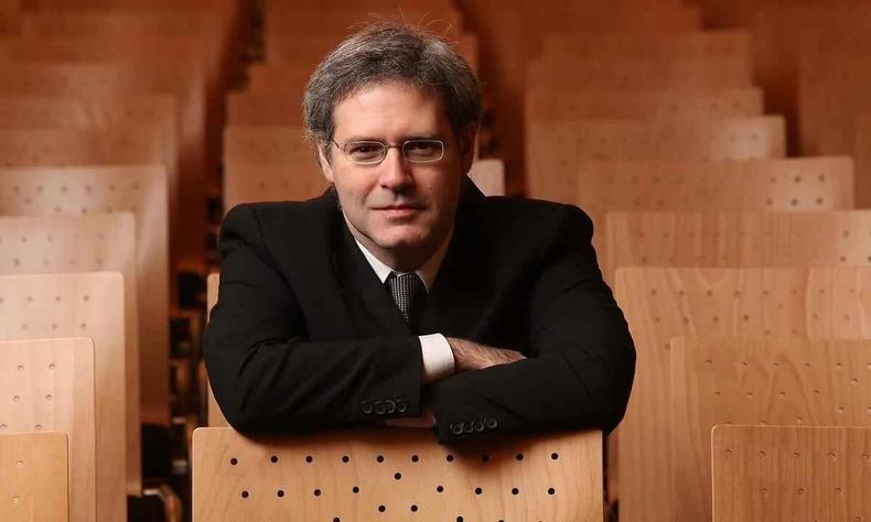Olhando para a cmera, o pianista Eduardo Monteiro est sentado na plateia de um teatro, com as mos nas costas da poltrona 