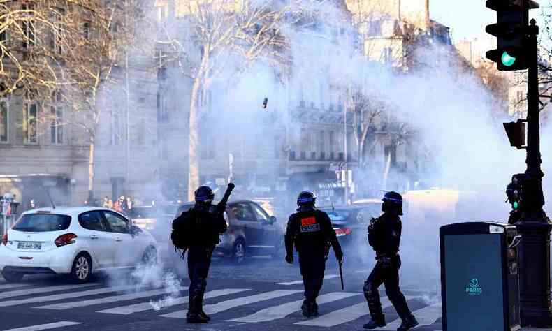 Um policial antimotim francs dispara uma lata de gs lacrimogneo na Champs Elysees, em Paris, em 12 de fevereiro de 2022, quando comboios de manifestantes chamados 'Convoi de la Liberte' chegavam  capital francesa