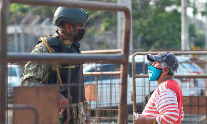militar atrs de uma barreira de grades conversa com morador de Guayaquil em frente ao presdio onde 68 detentos morreram