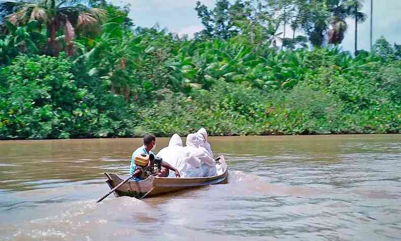 Equipes levando atendimento de barco, com roupas de proteo, a comunidades ribeirinhas