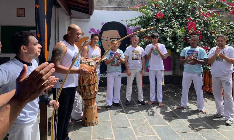 Grupo de capoeira, onde todos esto vestidos de branco, batendo palmas 