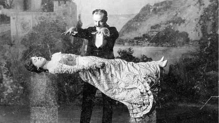 Imagem em preto e branco de um mgico levitando uma mulher