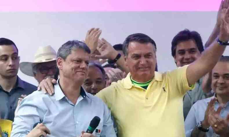 Tarcsio sendo abrao por Bolsonaro, com ambos sorrindo