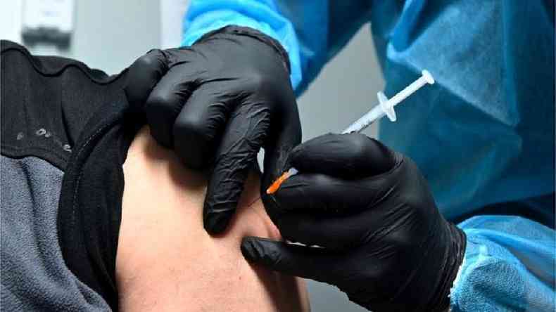 Pessoa injeta vacina no brao de outra