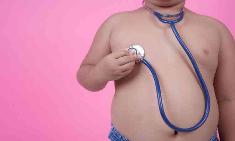 Criança obesa segurando um estetoscópio no coração 