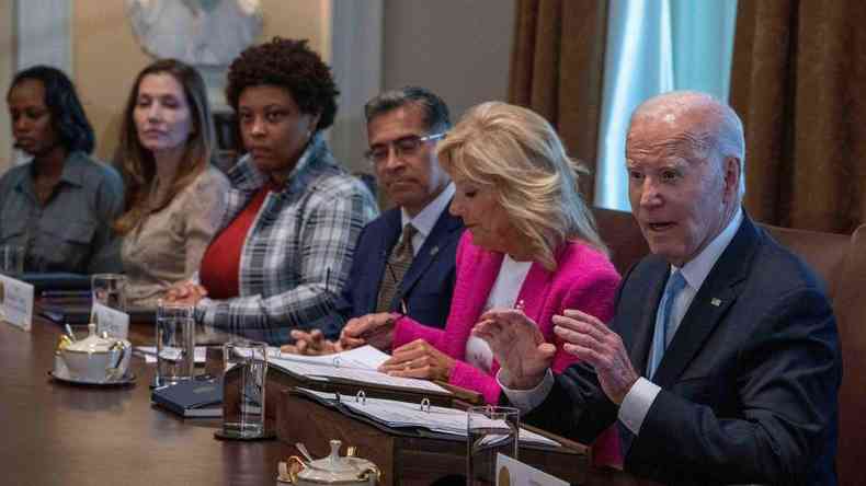Joe Biden falando sentado em uma mesa com outras cinco pessoas