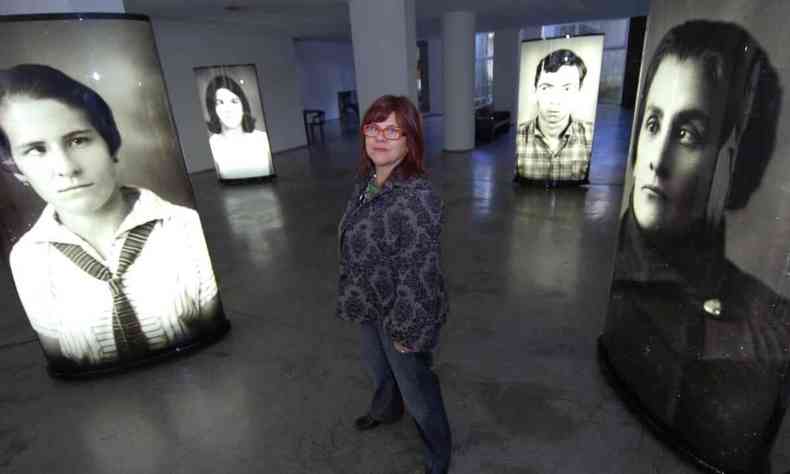 Artista Rochelle Costi posa entre fotografias na Galeria Celma Albuquerque, em BH