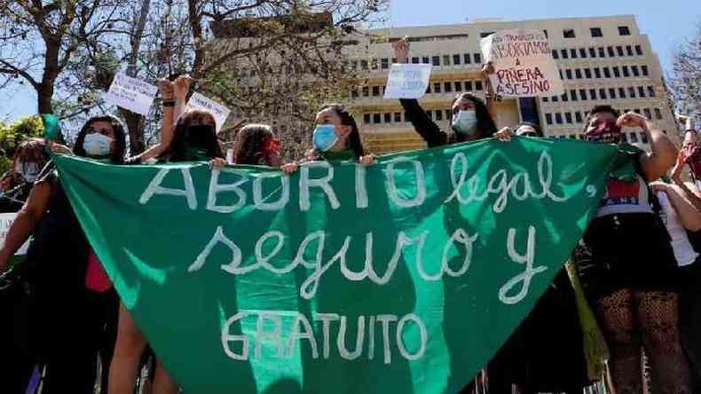 Mulheres na Argentina com um grande tecido verde que diz 'Aborto legal, seguro e gratuito'
