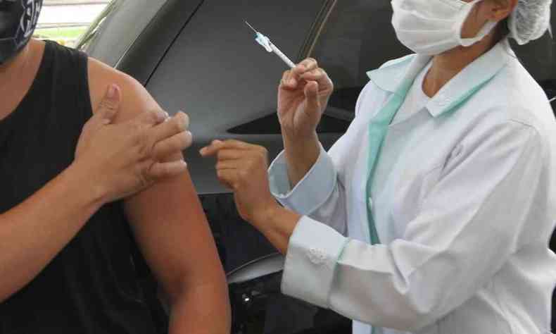 Enfermeira com a injeo na mo para vacinar uma pessoa contra a COVID-19