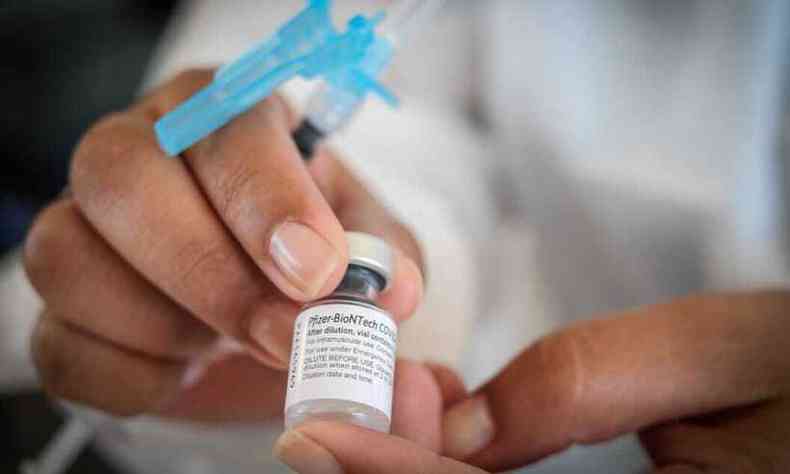 Mãos de enfermeiro mostram frasco de vacina da Pfizer