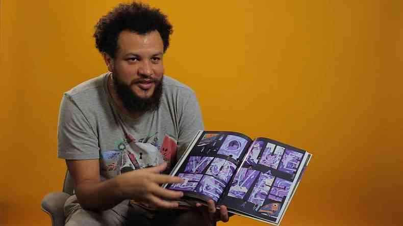 Jefferson Costa segura livro de quadrinhos com as pginas abertas