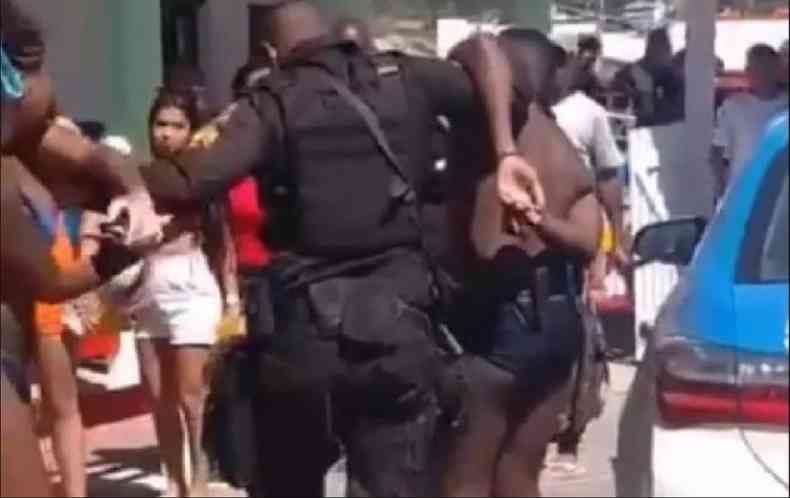 Turista em roupas de banho sendo encaminhado algemado por policial