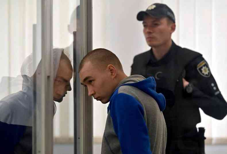 Soldado observa pelo vidro o anncio da sentena pelo crime de guerra que confessou ter cometido