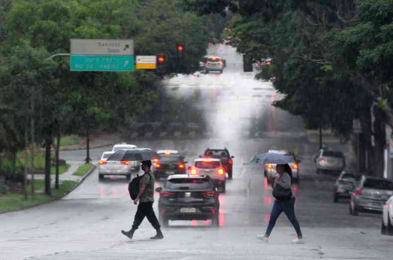 pessoas atravessando a rua em dia de chuva