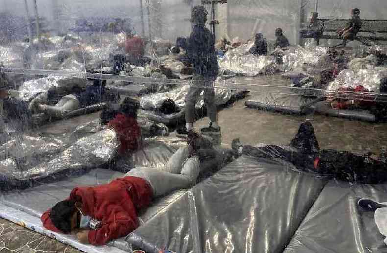 Jovens migrantes na instalao so mantidos em reas lotadas separadas por lonas de plstico(foto: Reuters)