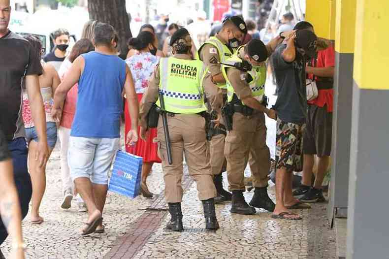 Policiais fazem segurança e revistam suspeitos para dar segurança no Natal Multidão de consumidores transitando com sacolas e máscaras pela Rua Curitiba para compras natalinas