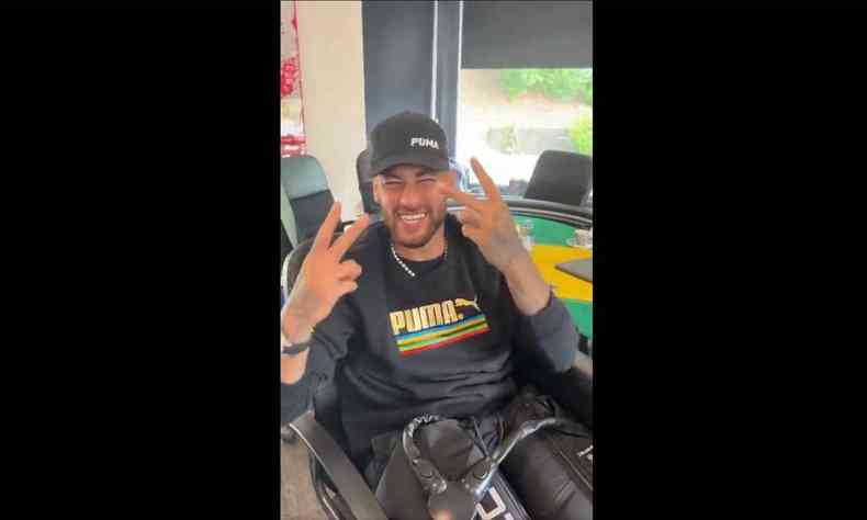 Neymar sentado em uma cadeira gamer fazendo o nmero 22 com as mos