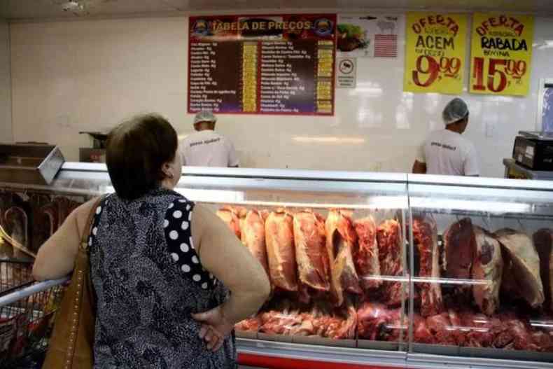 Mulher observa os preos de carnes no aougue