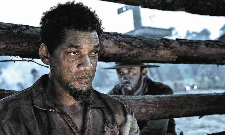 O ator Will Smith olha para a frente, contracenando com Ben Forster, atrs de cerca de madeira, no filme Emancipation 