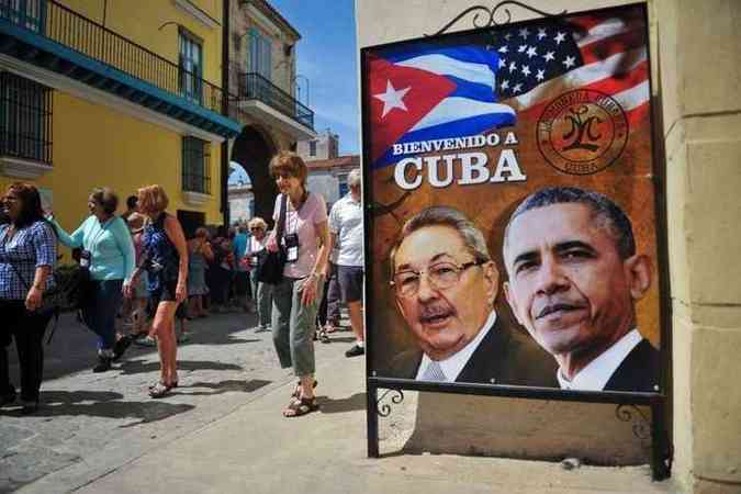 Turistas andam ao lado de cartaz com os presidentes de Cuba e dos Estados Unidos (foto: AFP PHOTO / YAMIL LAGE)