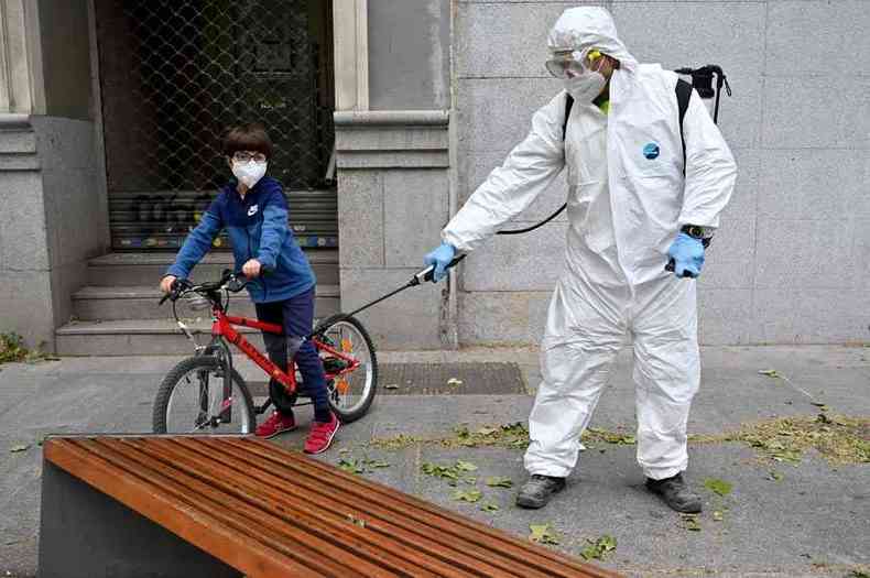 Em Madri, enquanto profissional de sade desinfeta objetos, o garoto com mscara aproveita a possibilidade de voltar  rua(foto: Gabriel Bouys/AFP)