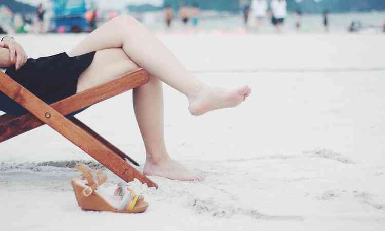 mulher sentada em uma cadeira na areia da praia