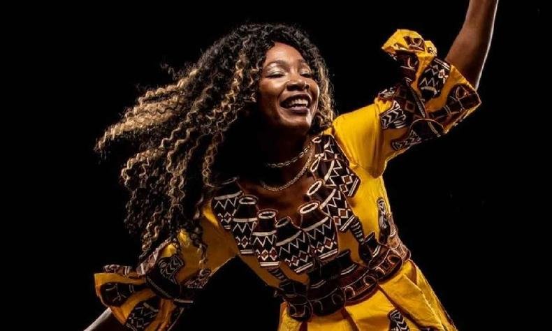 Fanta Konate usando roupas amarelas dan�ando em um fundo preto 