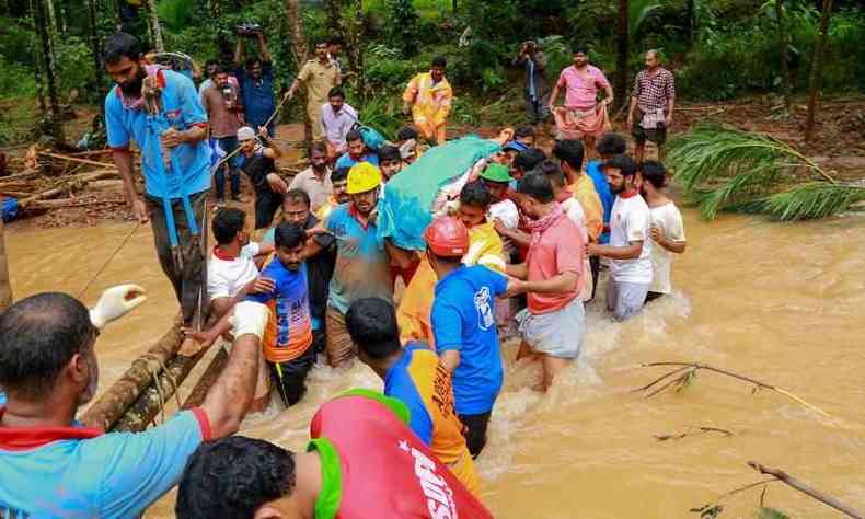 Equipes de resgate ajudam moradores a atravessar uma rea alagada em Kerala(foto: AFP/STR)