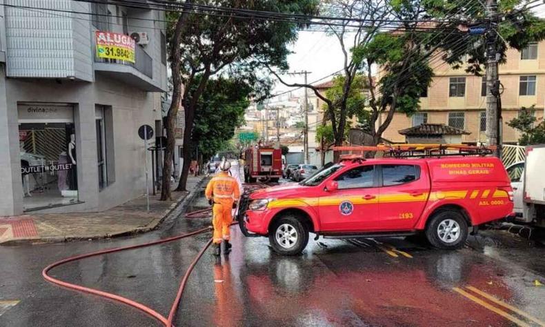 Viatura do Corpo de Bombeiros no meio da via. Asfalto molhado. 