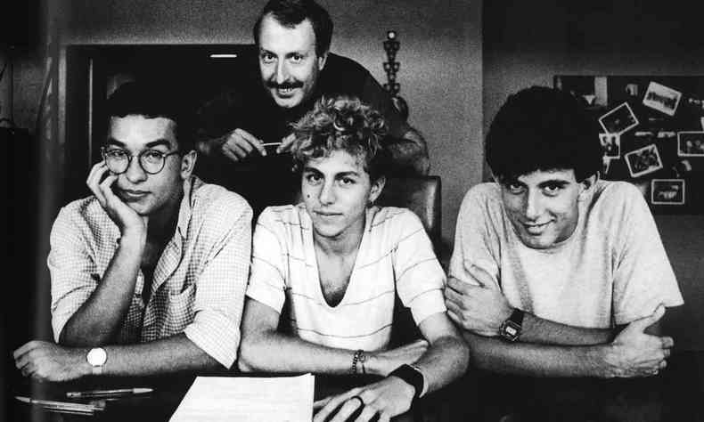  Muito jovens, Herbert Vianna, Bi Ribeiro e Joo Barone esto sentados  mesa,  frente de papel e caneta, no dia em que assinaram o primeiro contrato com a gravadora EMI
