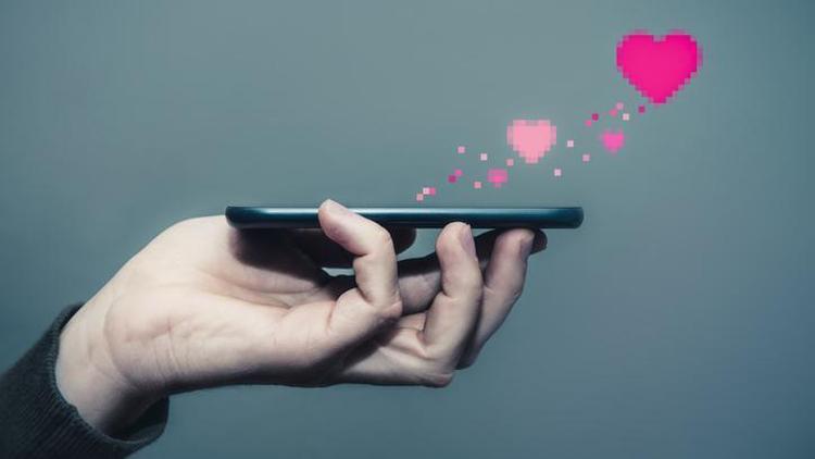 Pessoa segurando celular com símbolos gráficos de coração