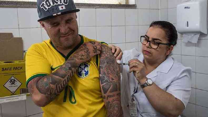 Homem com camisa da seleo brasileira recebe vacina no brao