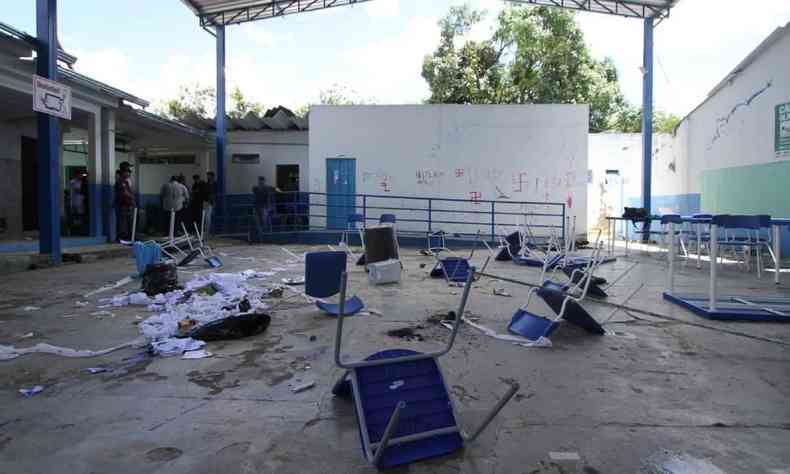 Na foto, ptio da escola com cadeiras viradas e quebradas e parede pichadas com a sustica, smbolo nazista