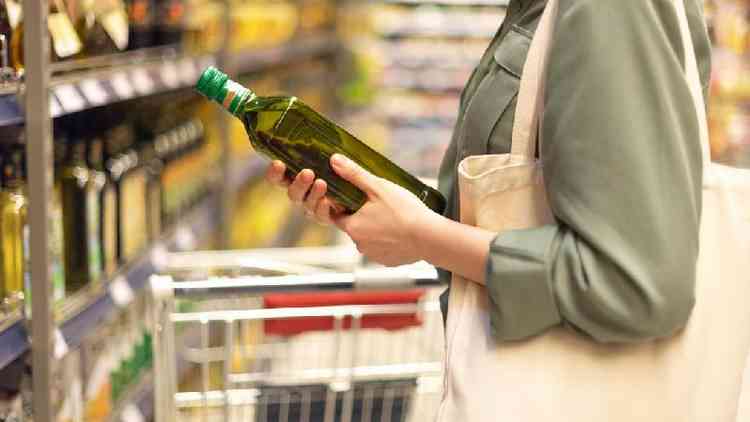 Mulher segurando garrafa de azeite de oliva em supermercado