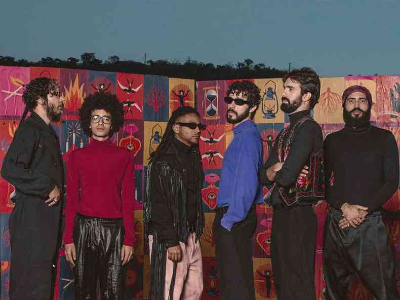 Seis integrantes do grupo A Outra Banda da Lua posam para foto em frente a muro grafitado